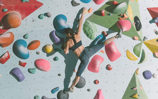 A strong woman athlete climbs on a colorful rock climbing wall